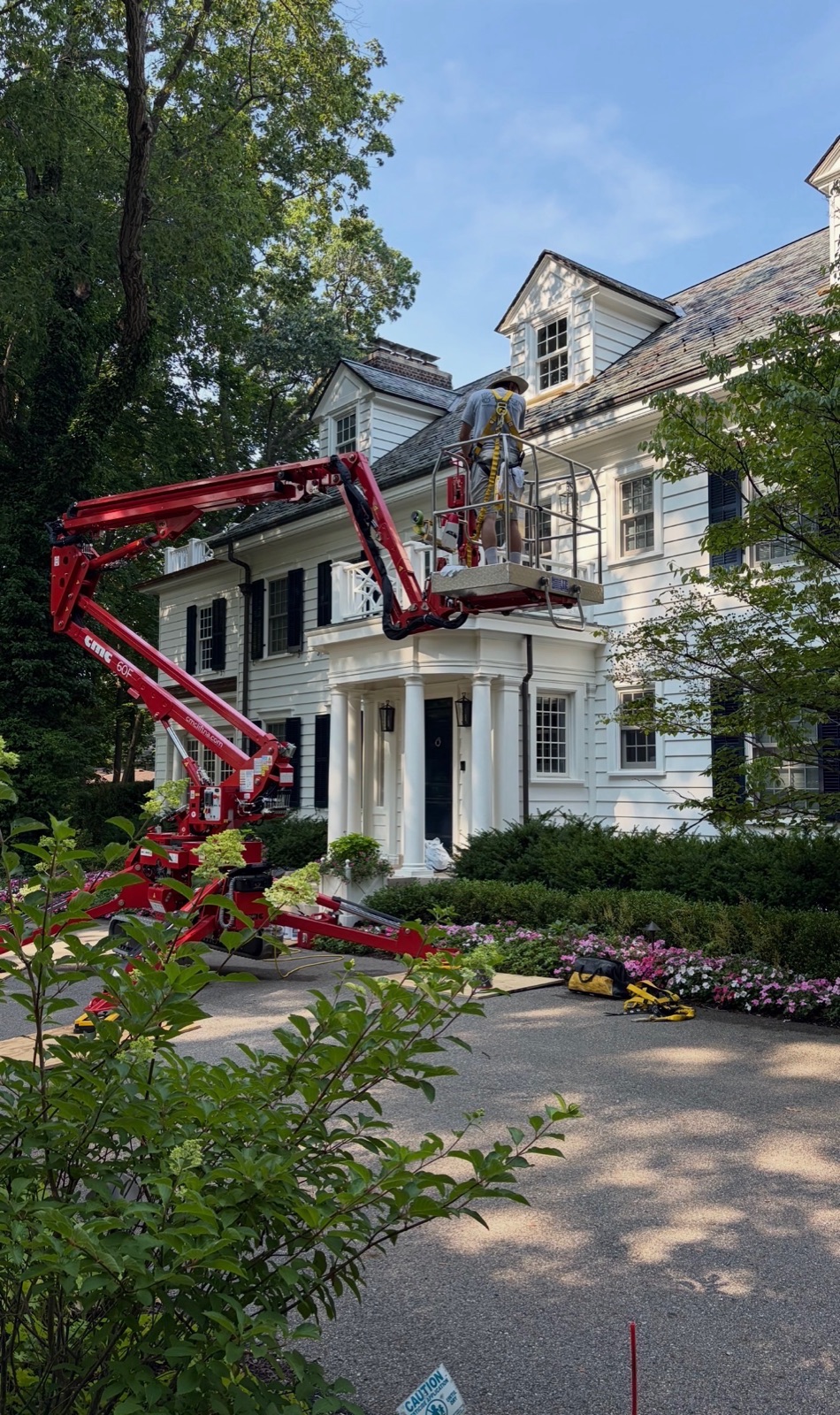 Crew working from an articulating lift on the portico of a white colonial estate