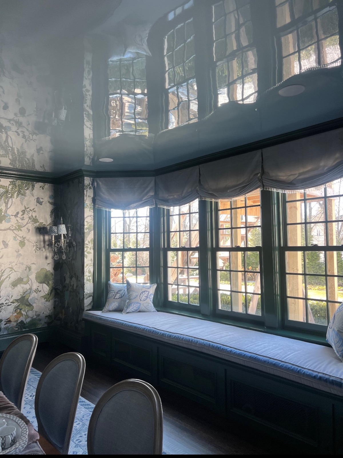 Lacquered deep-green ceiling over a leaded-glass window bay and window seat
