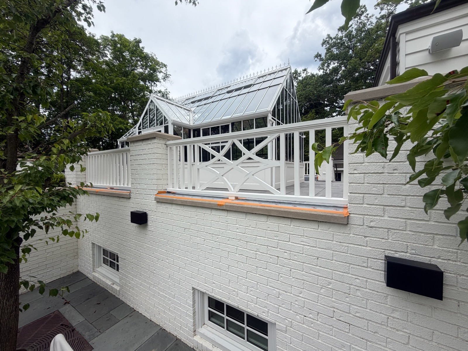 White-painted brick terrace wall and balustrade beneath a glass conservatory