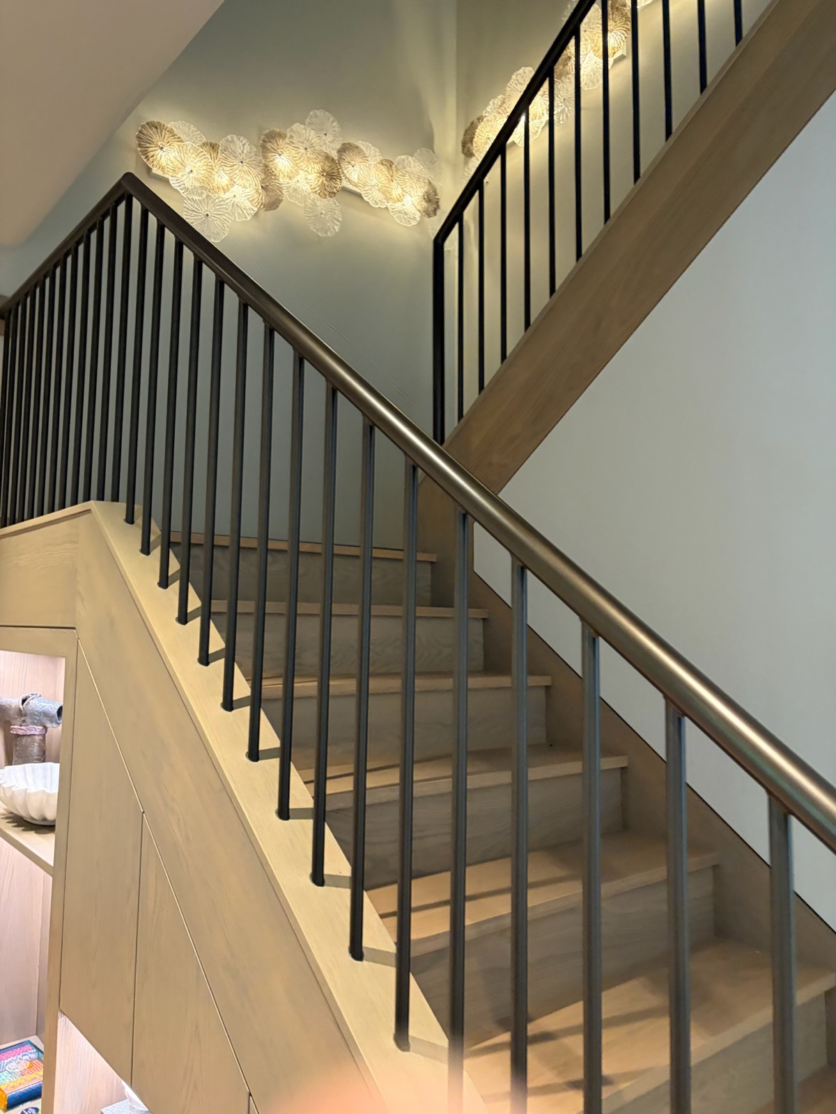 Stair hall with soft green walls, metal balusters and white-oak treads